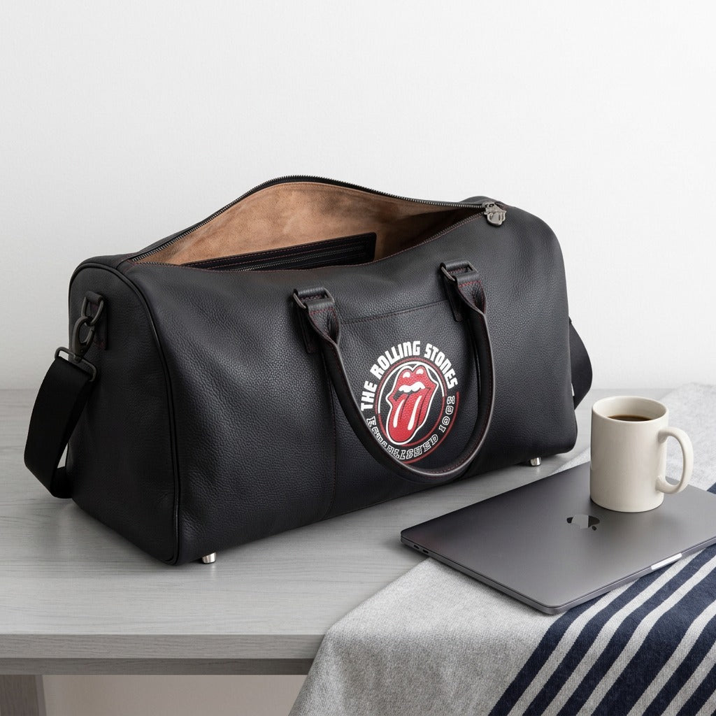 Bugatti The Rolling Stones Watts leather duffle bag next to a laptop and coffee mug for scale.