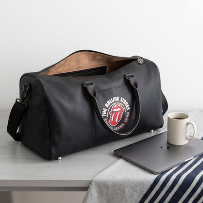 Bugatti The Rolling Stones Watts leather duffle bag next to a laptop and coffee mug for scale.