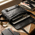 Bugatti Rolling Stones black leather messenger bag, open to show laptop and audio gear on a desk.