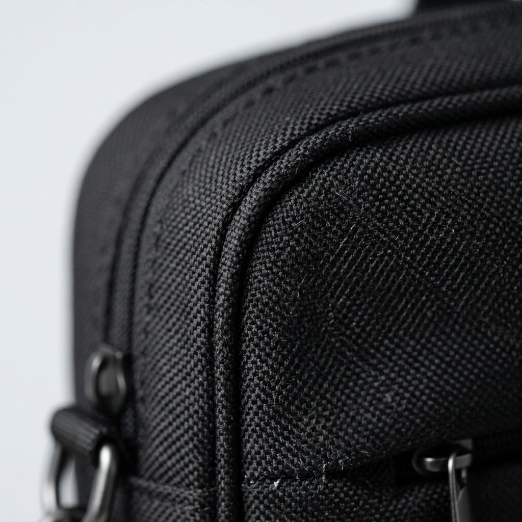 Macro detail of the black Nextech Nxt Poly laptop bag showing textured weave and durable stitching.