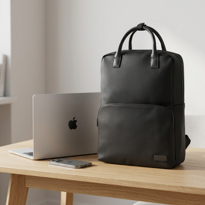 Black pebble grain Bugatti Contrast backpack on a wooden desk next to a laptop and smartphone.